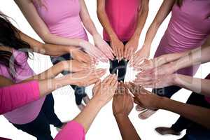 Women in pink outfits joining in a circle for breast cancer awar