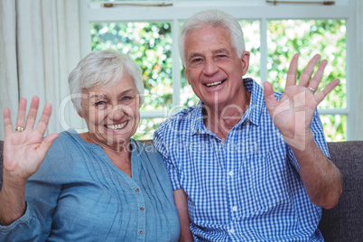 Portrait of happy senior couple waving hand