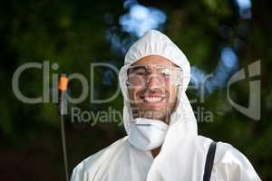 Close-up portrait of smiling man with pesticide sprayer