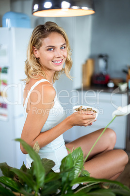Portrait of happy young woman having breakfast in kitchen