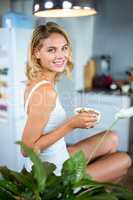 Portrait of happy young woman having breakfast in kitchen