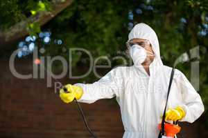 Man using insecticide while standing against tree