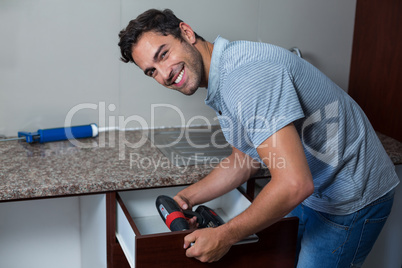 Portrait of happy man using cordless hand drill
