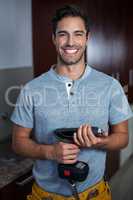 Portrait of cheerful man holding cordless hand drill