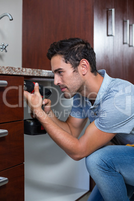 Man using cordless hand drill while crouching