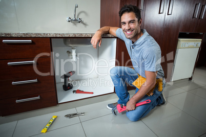 Portrait of smiling man holding pipe wrench