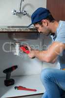 Man using pipe wrench while fixing sink pipe