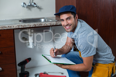 Portrait of smiling man writing on clipboard