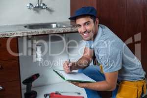 Portrait of smiling man writing on clipboard