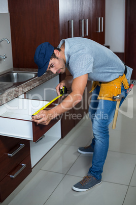 Full length of man measuring drawer size