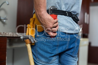 Rear view of man putting pipe wrench in pocket