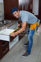 Full length portrait of man measuring drawer size