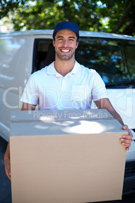 Portrait of happy delivery man holding cardboard box