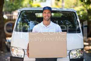 Portrait of smiling delivery person holding cardboard box