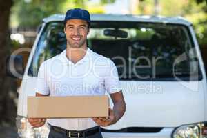 Cheerful delivery person holding cardboard box