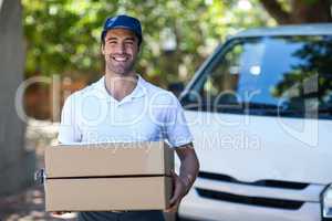 Portrait of smiling delivery man holding cardboard box