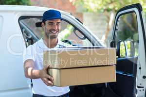 Smiling delivery man giving cardboard boxes