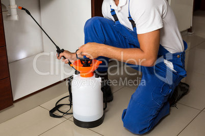 Midsection of man spraying insecticide on sink pipe