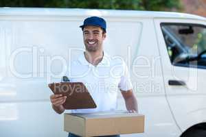 Smiling delivery man with clipboard and cardboard box