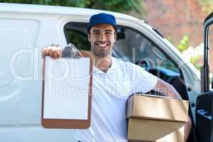 Smiling delivery man showing clipboard