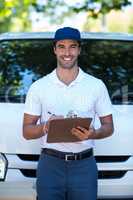 Portrait of smiling delivery man writing in clipboard