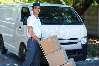 Portrait of smiling delivery man carrying cardboard boxes