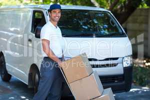 Portrait of smiling delivery man carrying cardboard boxes