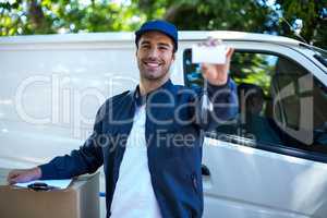 Portrait of smiling delivery man showing business card