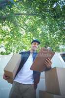 Low angle view of smiling delivery man holding clipboard