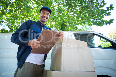 Low angle portrait of smiling delivery man holding clipboard