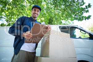Low angle portrait of smiling delivery man holding clipboard