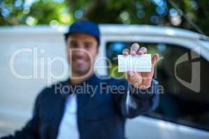 Smiling delivery man showing business card