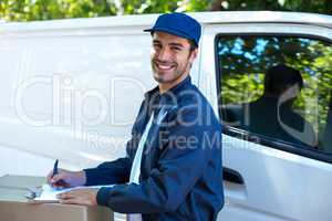 Portrait of happy delivery person writing in clipboard
