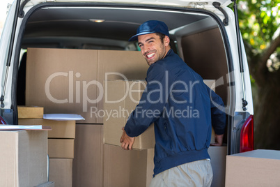 Happy delivery man loading cardboard box in van