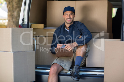 Portrait of smiling delivery person with clipboard