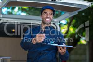 Smiling delivery person giving clipboard for signature