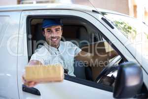 Smiling delivery man giving cardboard box