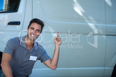 Smiling delivery man pointing at van