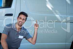 Smiling delivery man pointing at van