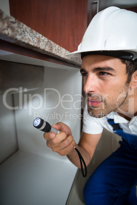 Man using torch while kneeling y sink