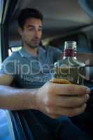 Slumped young man holding alcohol bottle