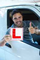 Handsome man showing thumbs up while holding L plate
