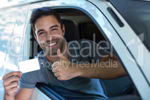 Handsome driver showing thumbs up while holding blank card