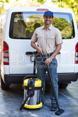 Portrait of happy janitor with vacuum cleaner