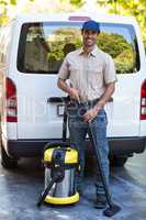 Portrait of happy janitor with vacuum cleaner