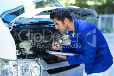 Male mechanic examining engine