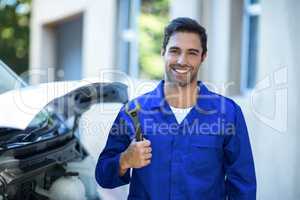 Portrait of confident mechanic holding wrench