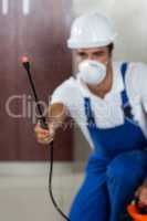 Manual worker spraying insecticide in kitchen