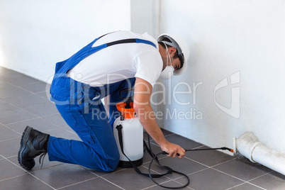 Manual worker spraying insecticide on pipe