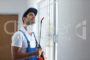 Thoughtful pest worker with sprayer looking up